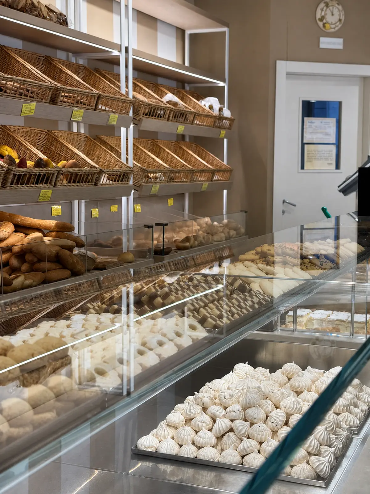 Il banco del pane Cadenaro: i cesti di vimini sugli scaffali, i filoni in vetrina e il vassoio delle meringhe