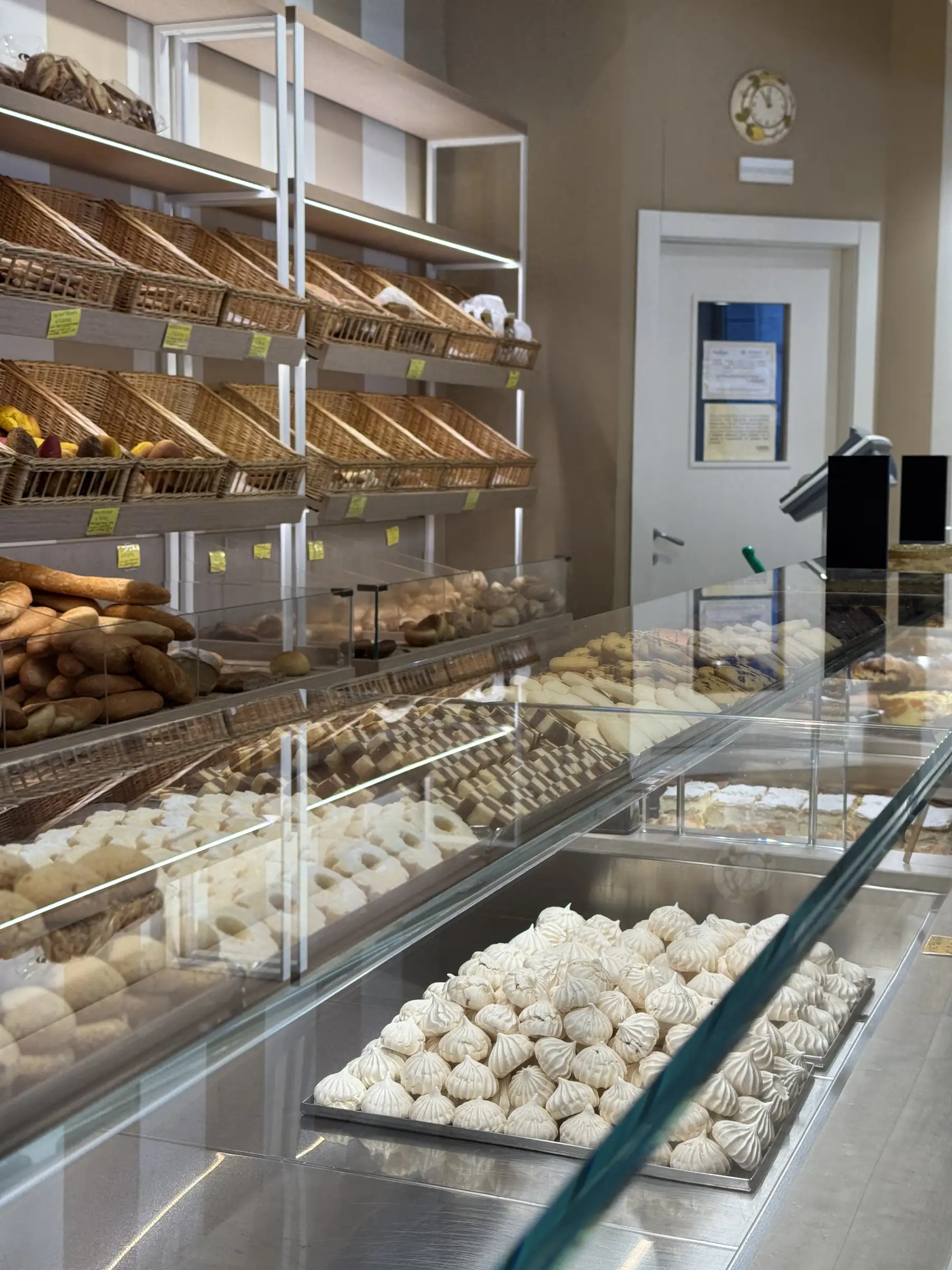 Il banco del pane Cadenaro: i cesti di vimini sugli scaffali e il vassoio delle meringhe in vetrina