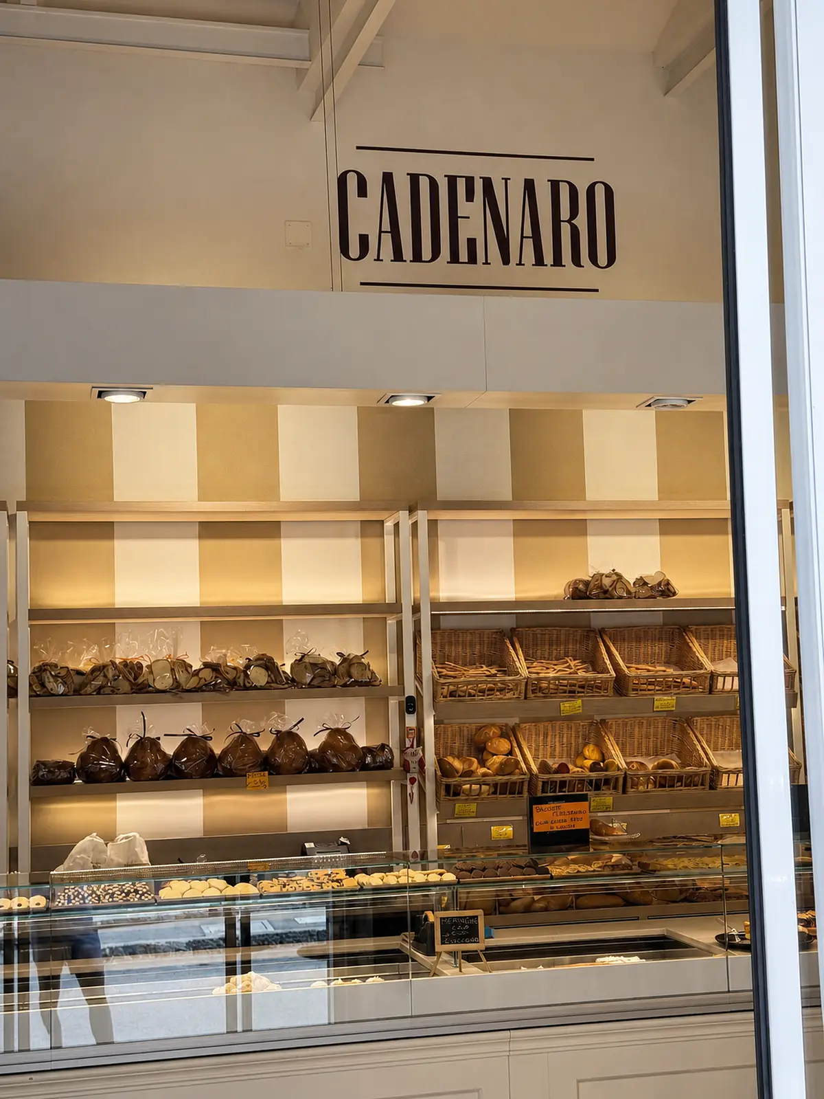 Il marchio Cadenaro dipinto sulla parete del negozio, sopra gli scaffali con il pane e i dolci incartati