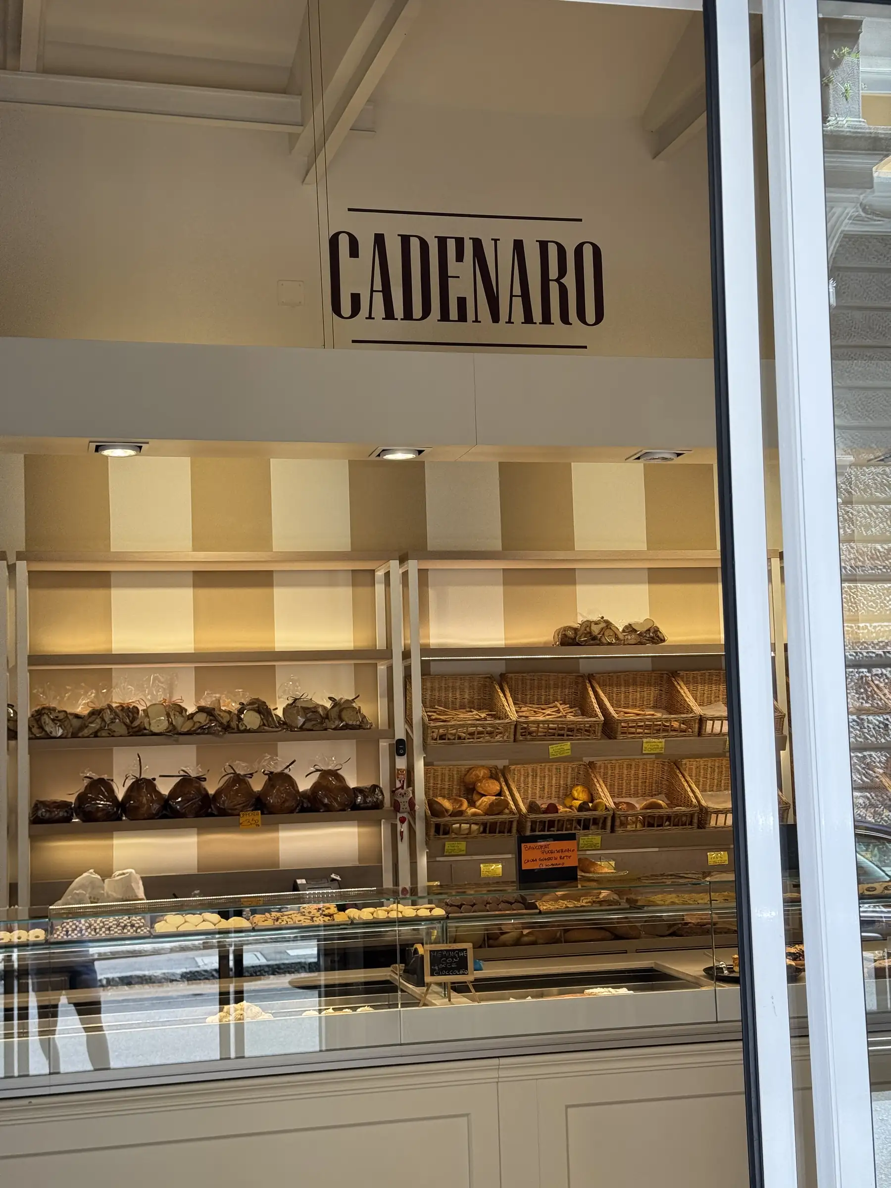 Il marchio Cadenaro dipinto sulla parete del negozio, sopra gli scaffali con il pane e i dolci incartati