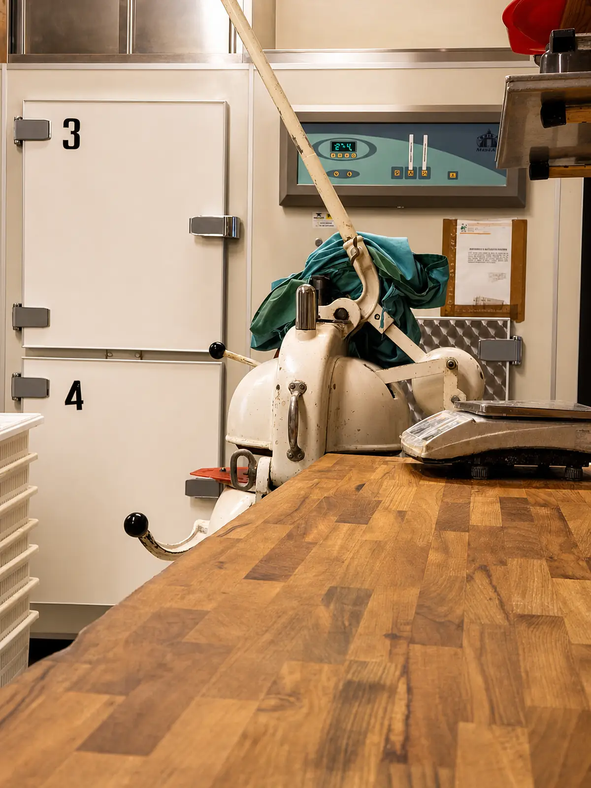 Il banco di legno del laboratorio con la spezzatrice e la bilancia, davanti alle celle di lievitazione